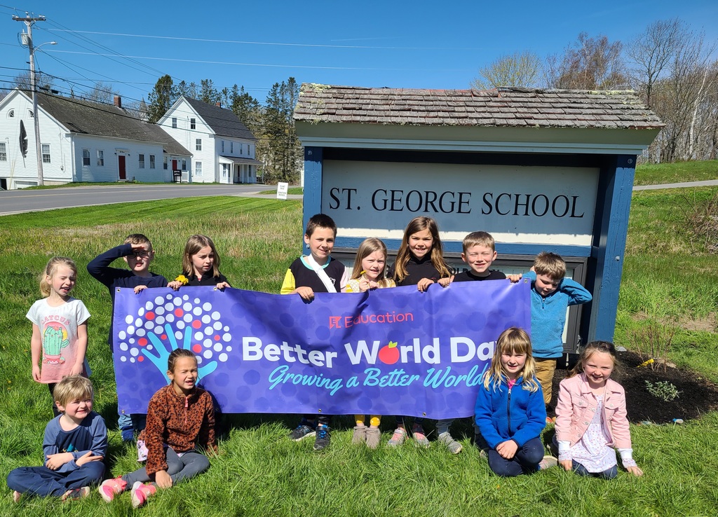 Students holding a better world day sign up in front of St. George school sign